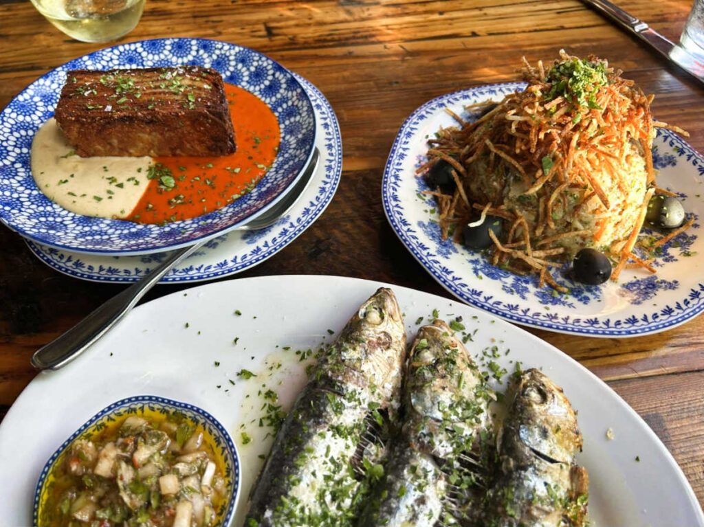 A table filled with a variety of dishes and a glass of wine