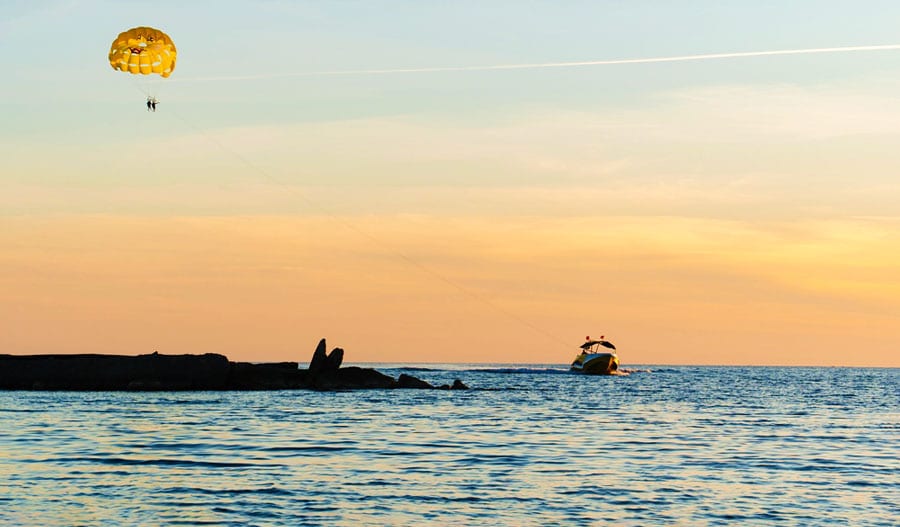 View of a person parasailing in Long Beach and the colorful sky during sunset