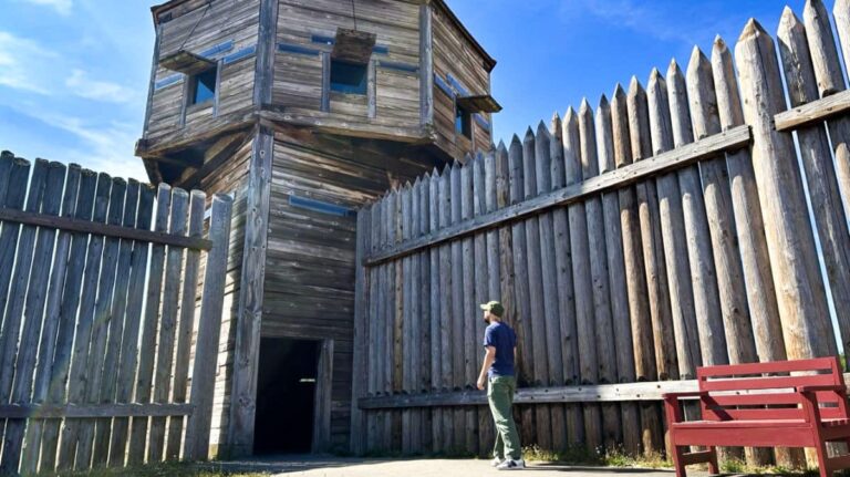 The author's husband, looking at one of the wooden buildings in Fort Vancouver