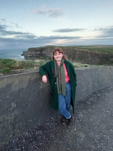 Louise Wylie smiling for a photo in Cliffs of Moher, Ireland
