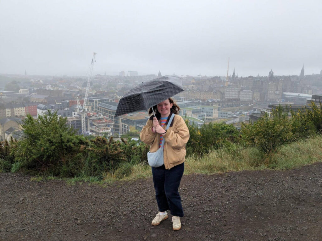 The author Louise Wylie standing at the top of Calton Hill on a pretty windy day