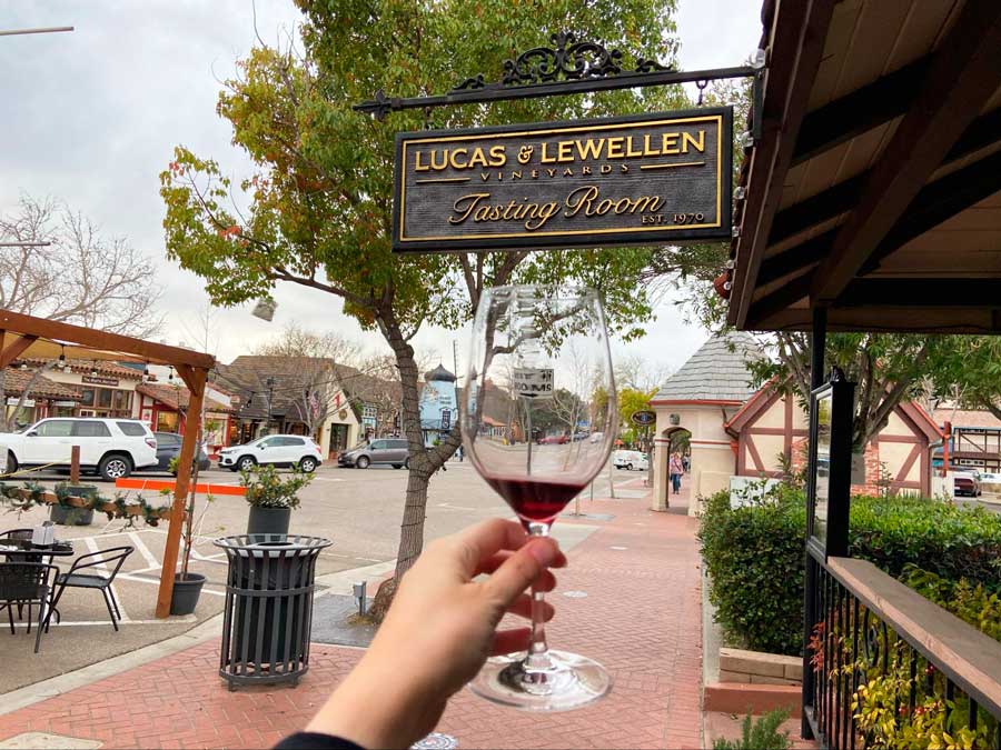 The author holding a glass of wine in front of Lucas & Lewellen Tasting Room