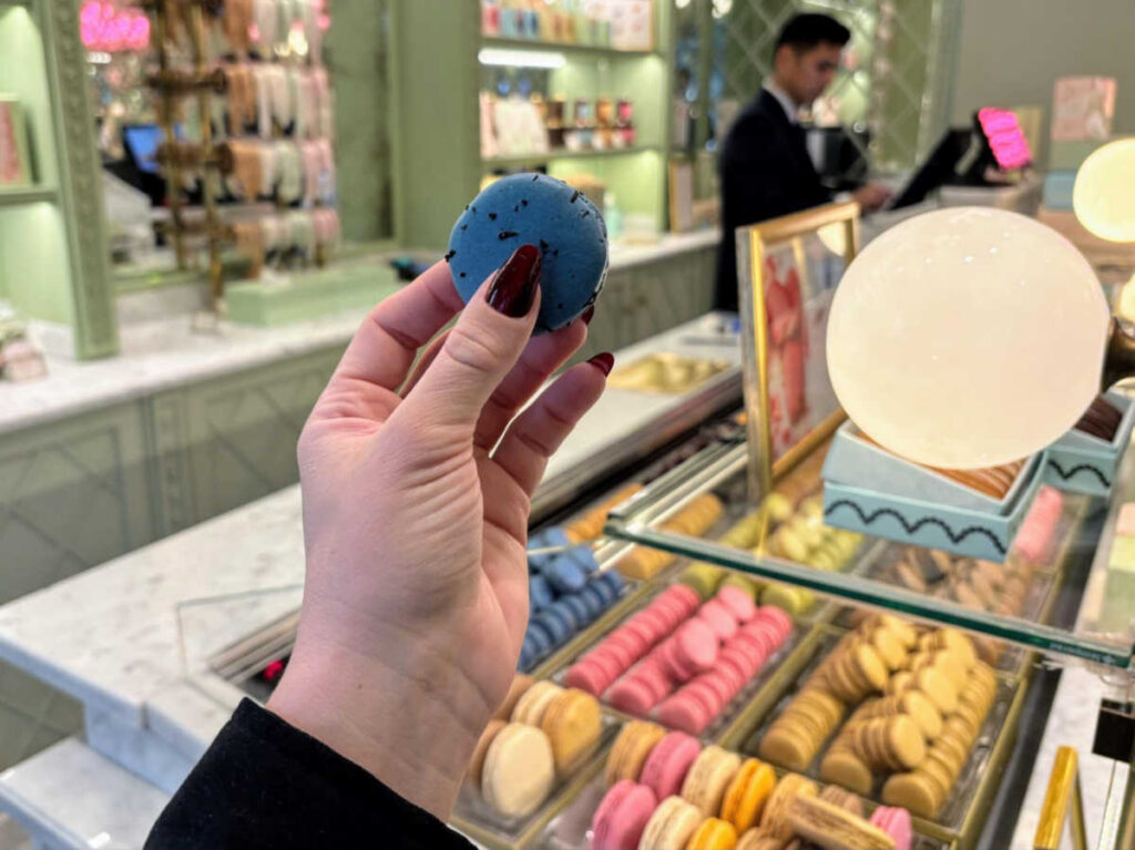 A hand holding a macaron at Ladurée