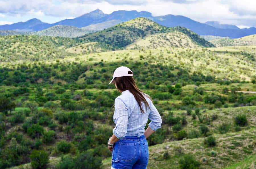 A woman at the peak of the mountain with a stunning view of the Santa Rita Mountains.