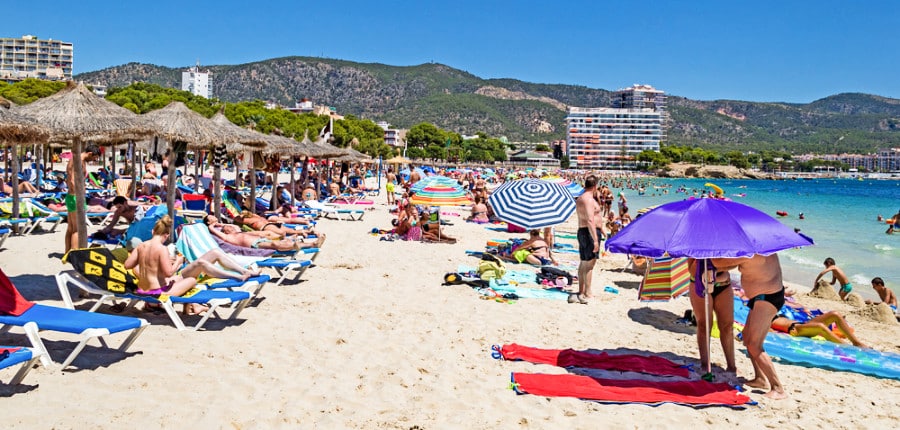 Tourists on the sandy beach enjoying the magnificent view and sun during a summer day in Magaluf