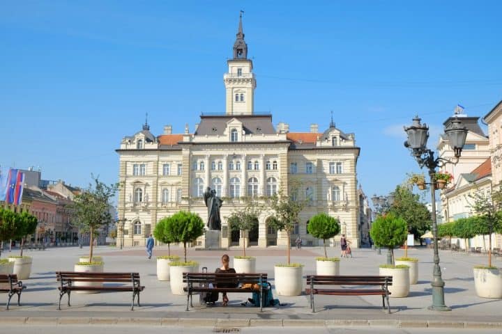 A woman sitting on the bench in front City Hall in main square of Novi