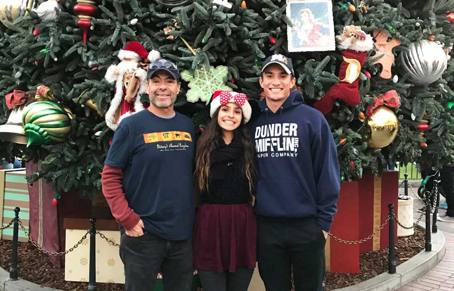 The author with her brother and father posing for a photo with the giant Christmas tree on the Main Street