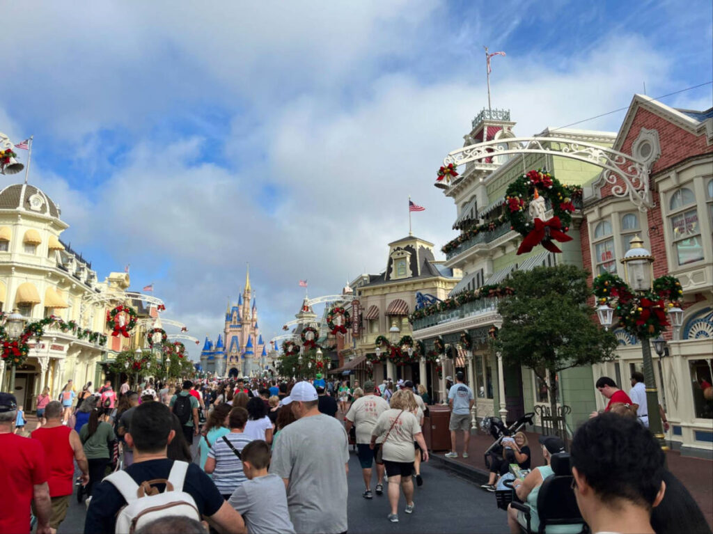 Crowd of people walking along the Main Street USA adorned with holiday decors