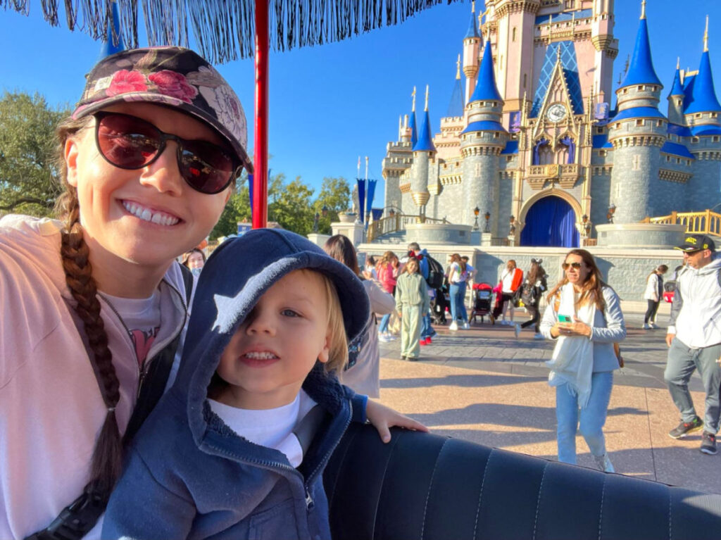 Author Katie Neufeld and child in front of Cinderella Castle on a Main Street Vehicles