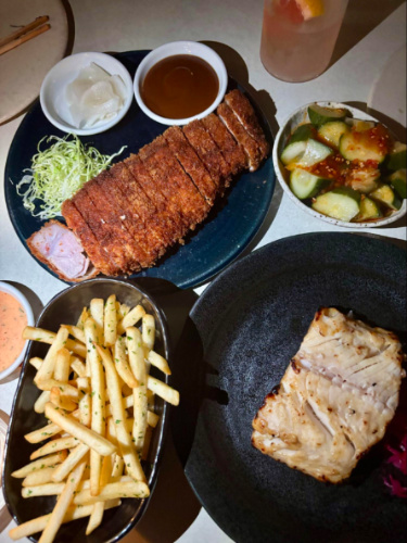 A table with pork cutlets, fish and fries at Mu