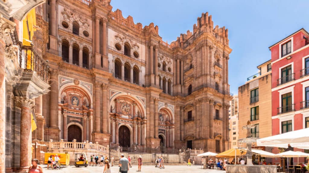 Façade of the great Málaga Cathedral with people wandering around