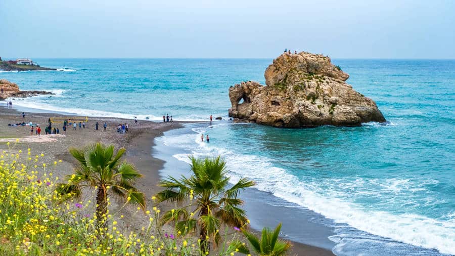 Overlooking view of people enjoying the rocking formation and pristine beach of Malaga