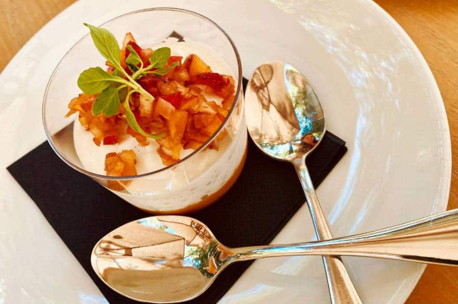 A small glass of tropical parfait with two spoons served on a plate