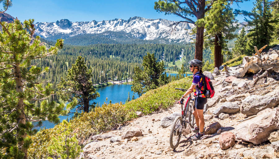 A woman with her mountain bike while enjoying the view of Mammoth Lakes.