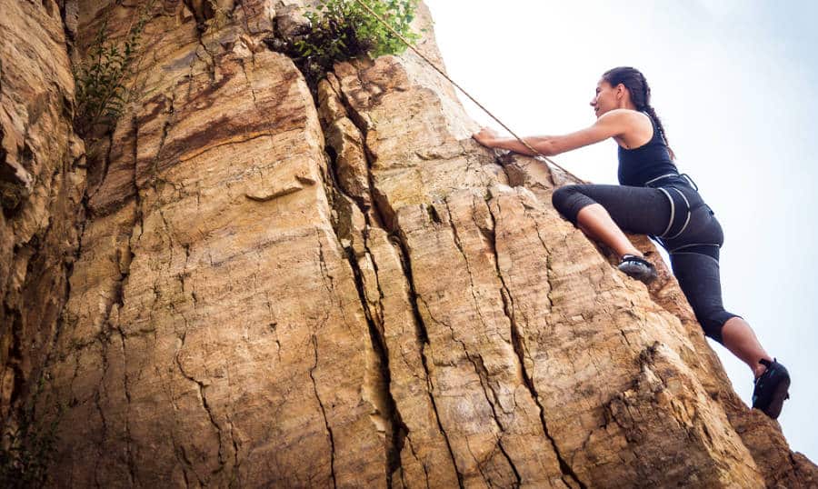 A woman rock climbing a steep mountain in California.