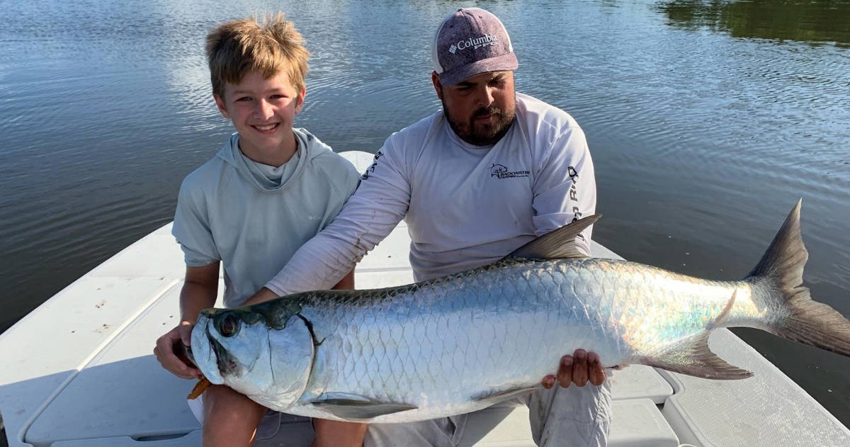 A man and child holding a huge catch of fish on the boat