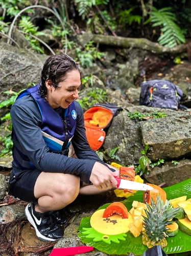 A man smiling while cutting the fruits