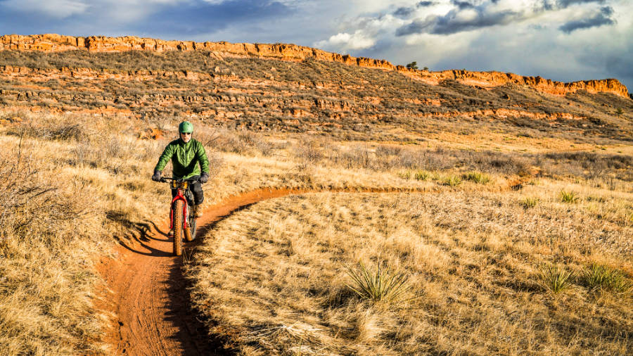 View of a man cycling along the trail of Lory State Park on a sunny day