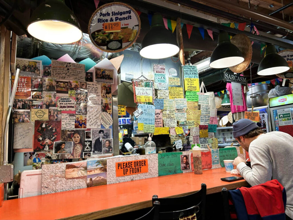A man eating at the dining area of Oriental Mart surrounded by the signs and letters