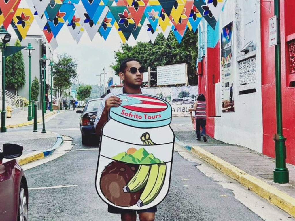 A man holding a hand painted cardboard at the colorful street