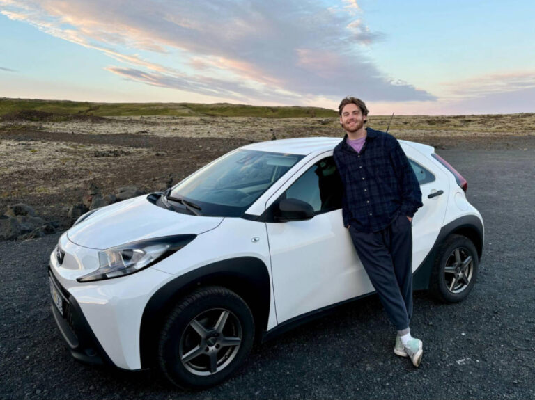 A man leaning on rented car with scenic view around