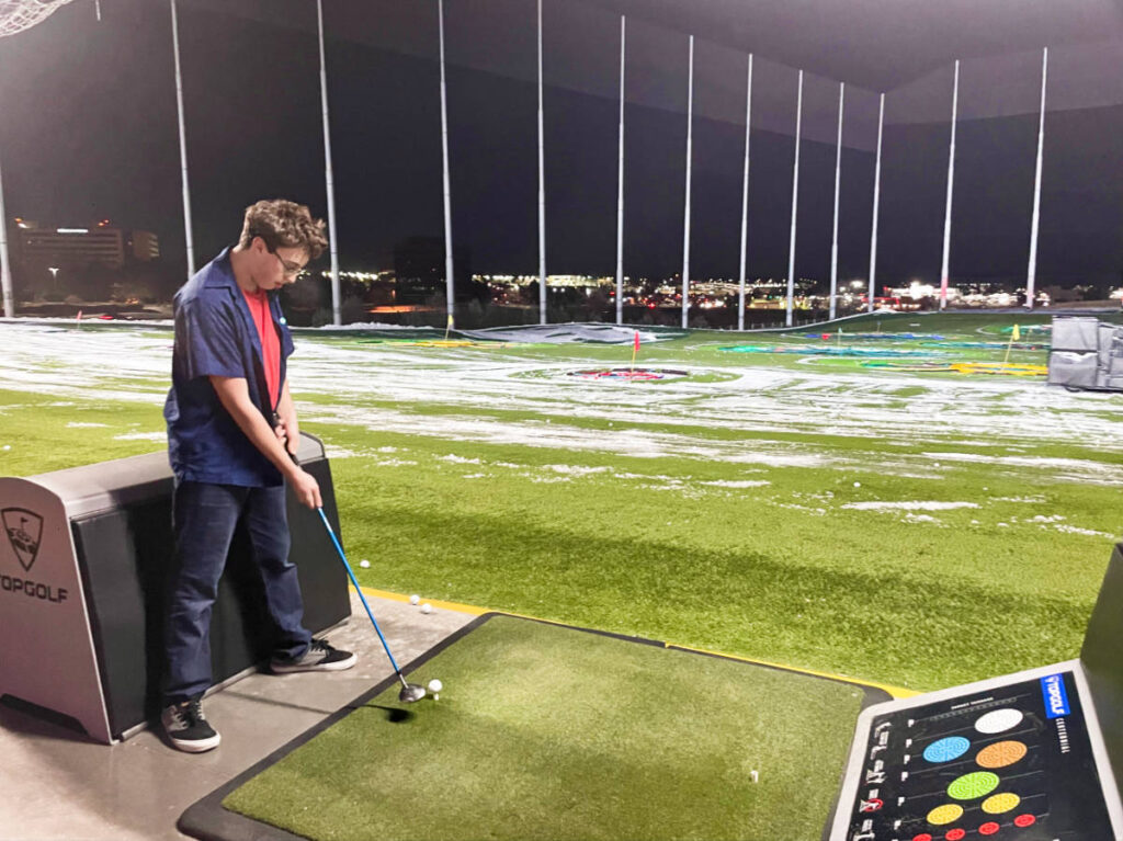 A man practicing golf at the Top Golf