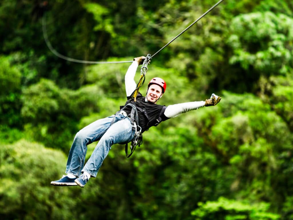 A man riding the zipline with the lush mountain view in the background