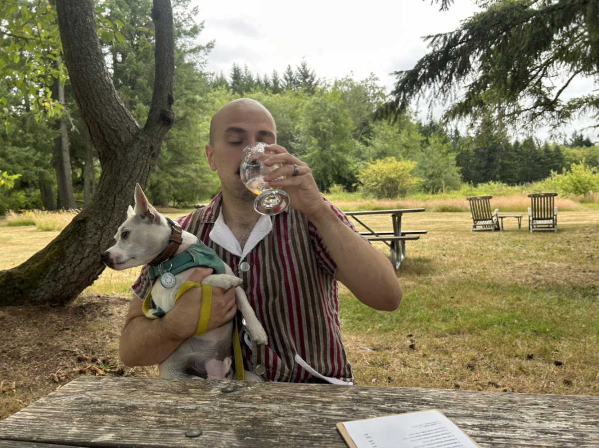 The author's husband drinking a cider while holding the dog