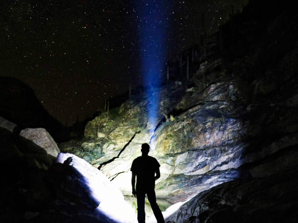 A man with flashlight under the starry sky in Tanque Verde Falls