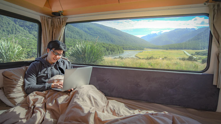 A man working on laptop on camper van