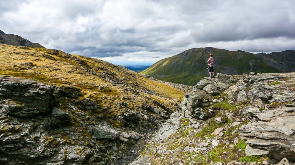 A man standing on a rock overlooking the view at Hatcher Pass