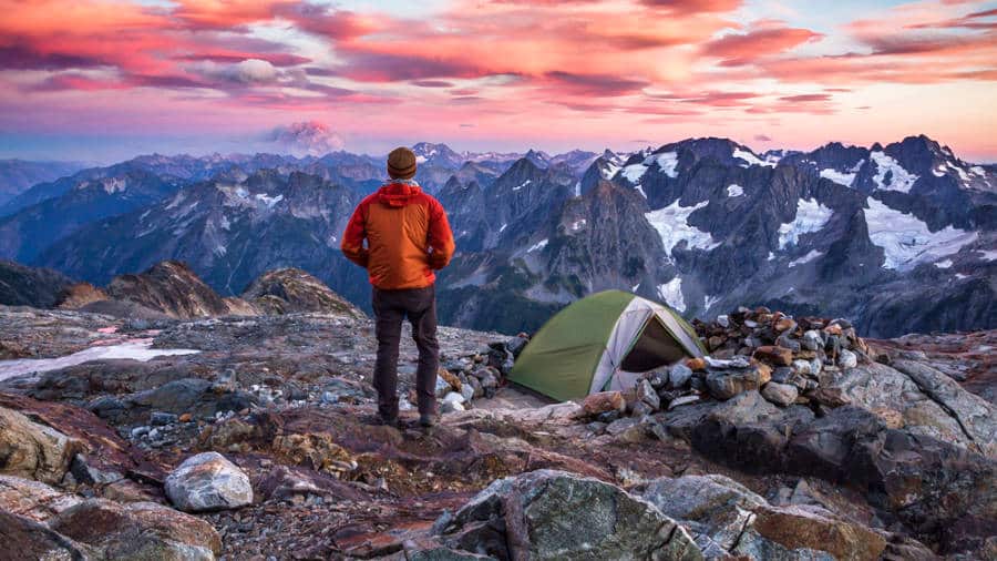 A hiker with a tent at the North Cascades National Park at sunset