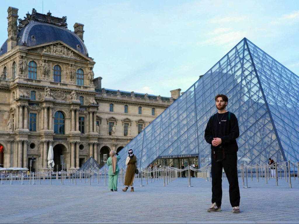 A man posing for a photo at the Louvre Museum