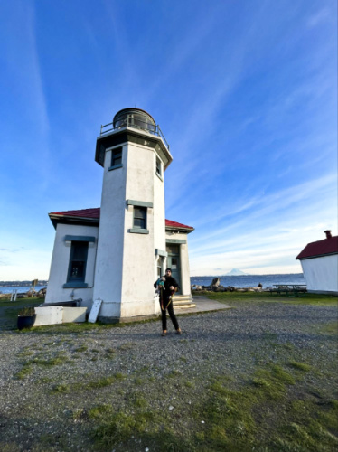 The author's husband posing in front of the Point Robinson Lighthouse with their dog