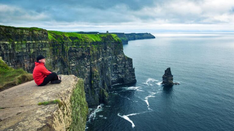 A hiker sitting on the cliff in Cliffs of Moher