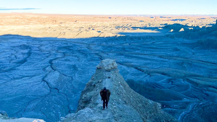 A man walking on a thin ledge before dusk