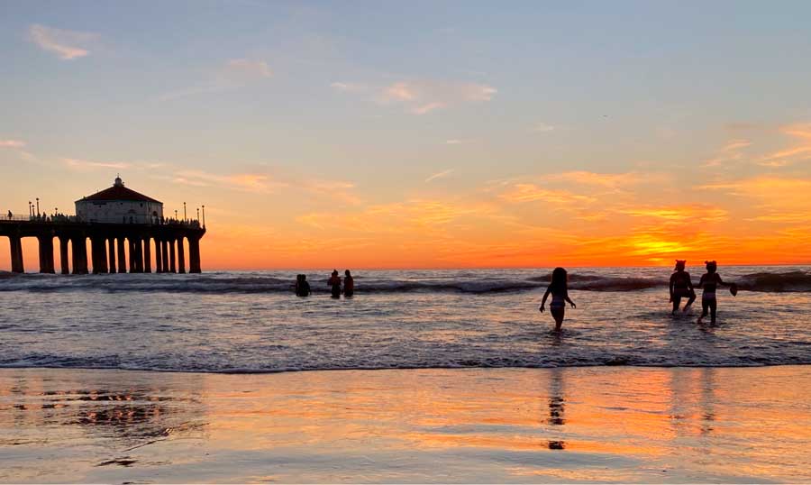 View of people in the Manhattan Beach and the colorful sky at sunset