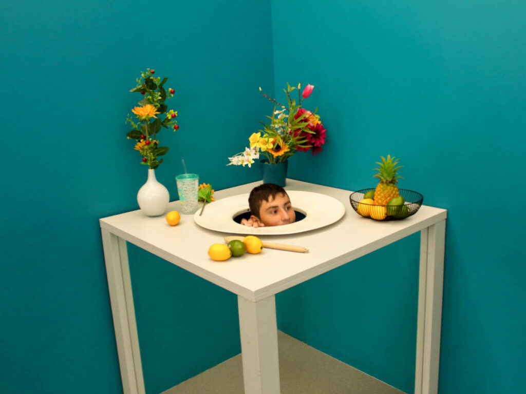 An optical illusion of a man's head coming out of the table