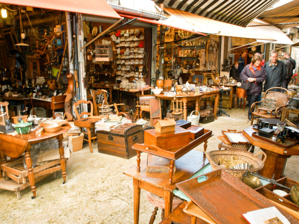 View of the people looking at the stores with displayed wooden products in Marché aux Puces