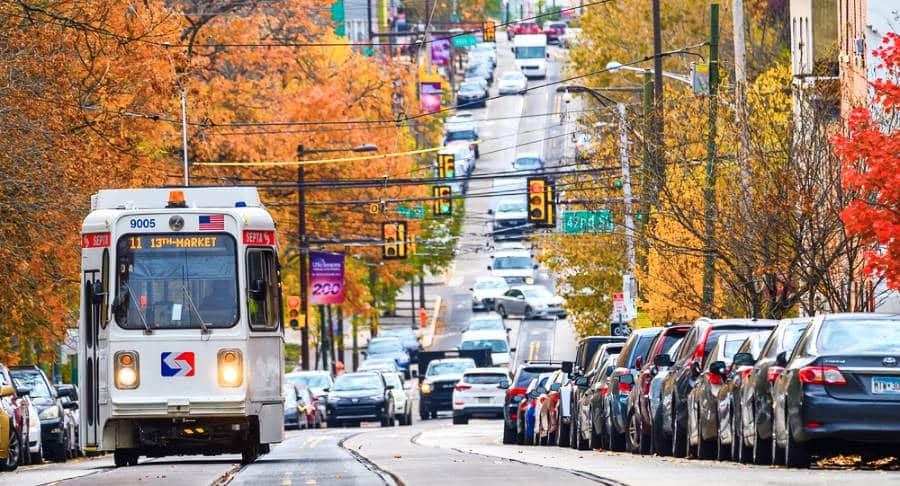 An approaching light rail trolley and parked cars around the avenue of Philadelphia