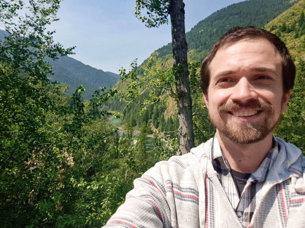 The author Matthew, smiling for a photo at the top of Glacier National Park