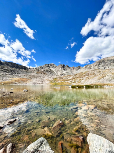 View of the crystal clear water of second alpine lake with a clear blue sky in the background in McCullough Gulch