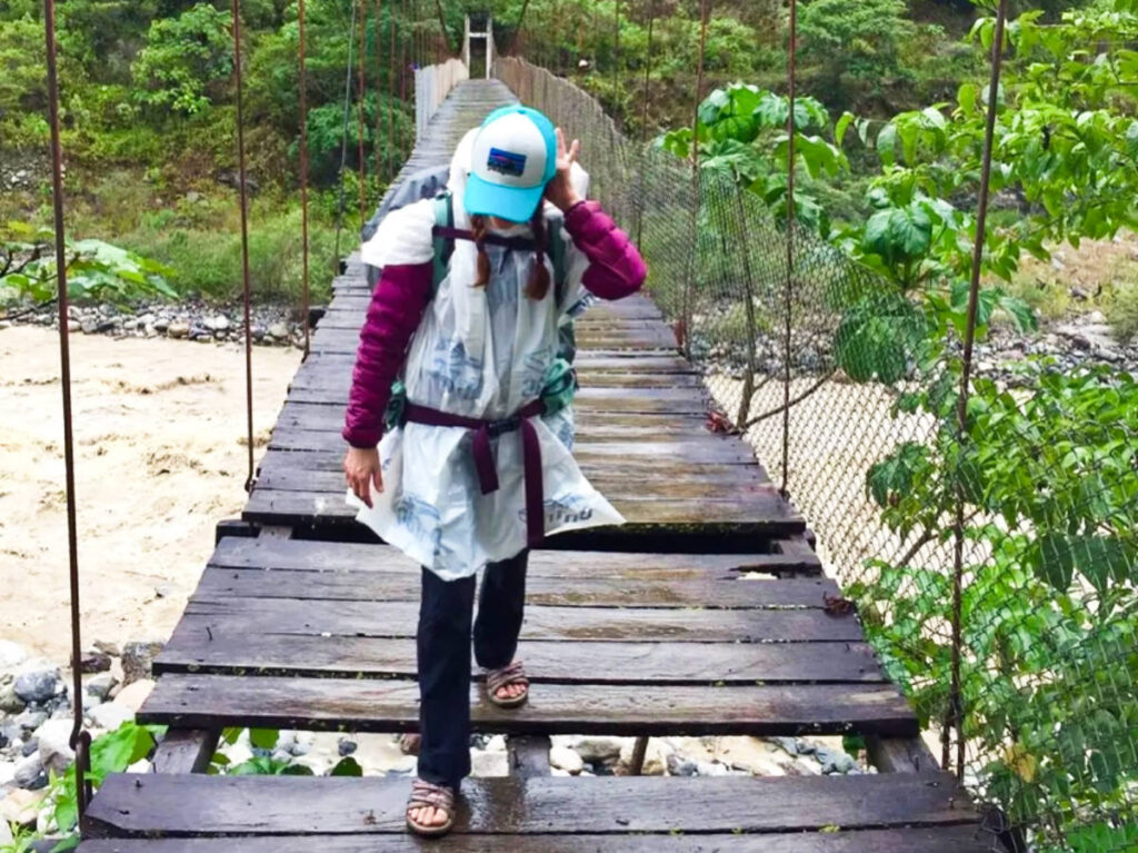 The author McKenna Mobley wearing a rain coat with her classic sandals while crossing the bridge