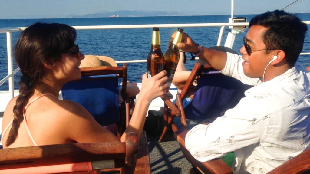 The author McKenna Mobley with a man drinking with bottle of beer on a ferry in Greece