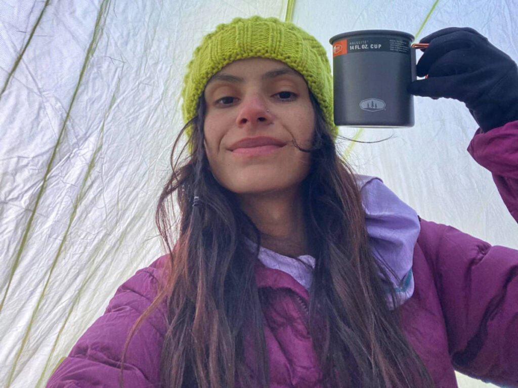 The author McKenna Mobley, holding a cup inside her camping tent at Upper Pines Campground