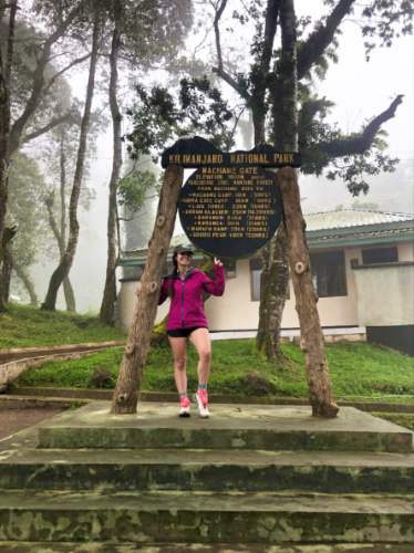 The author McKenna Mobley, posing for a photo at the entrance of Kilimanjaro National Park