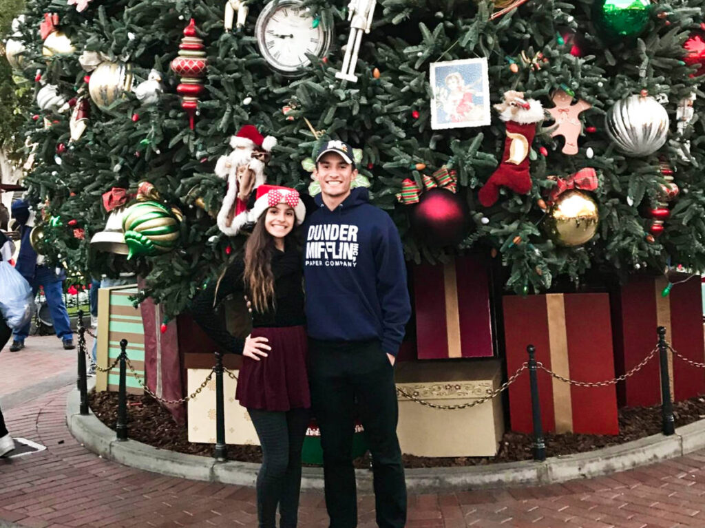The author McKenna Mobley with her brother, posing in front of the gigantic Disney Christmas tree