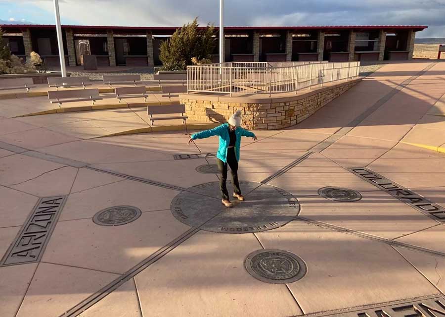 Travel Lemming writer McKenna standing at the Four Corners Monument