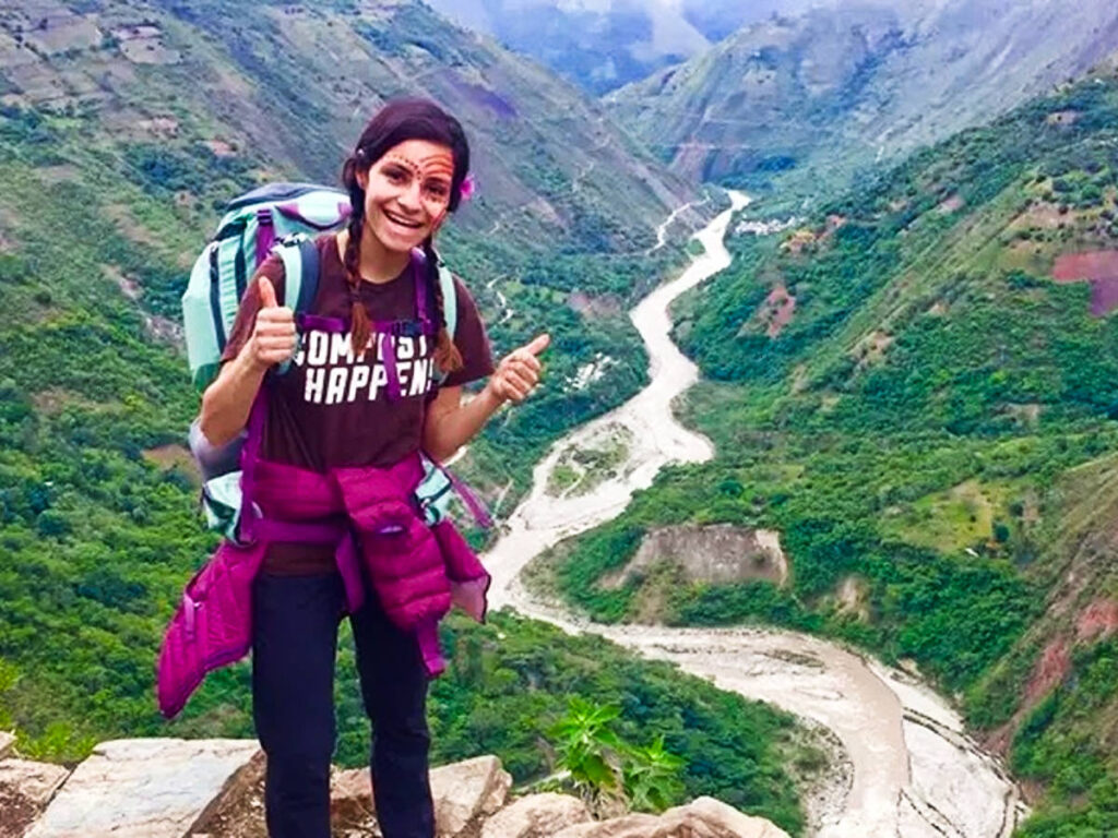 The author McKenna Mobley, posing for a photo with an overlooking view while carrying her backpack