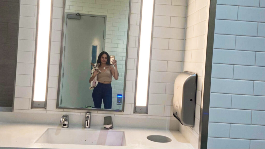 The author posing with her dog inside the bathroom at the airport